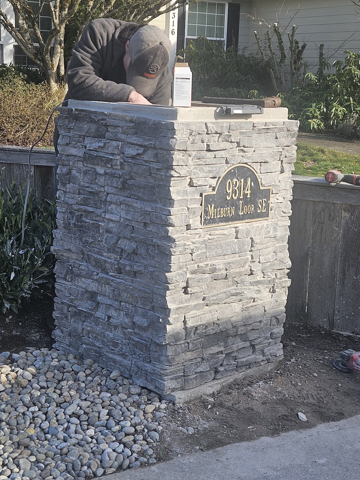 Close-up of a stacked-stone address pillar being installed